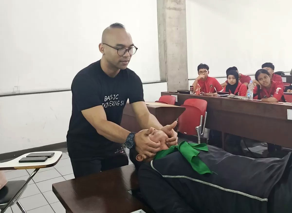 Instruktur memegang kepala dan leher peserta yang berbaring saat simulasi pertolongan pertama di ruang kelas. (Foto: Kabarindo.com)