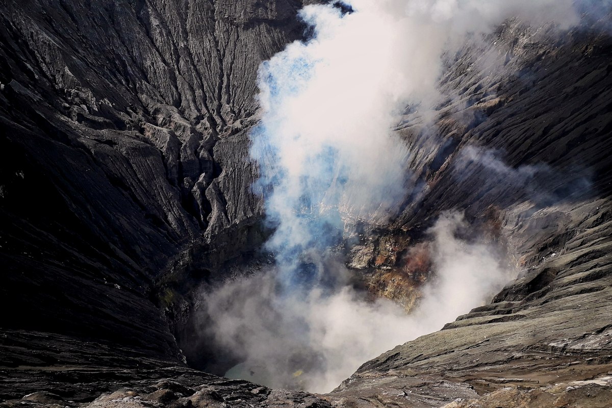Kawah Gunung Bromo dengan dinding kawah berlapis dan kepulan asap tipis.