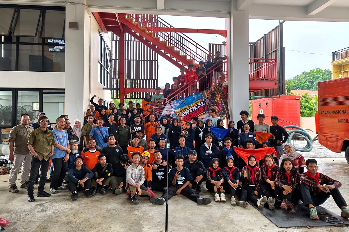 Foto bersama peserta dan instruktur di depan tangga besi dengan spanduk Pendidikan Pelatihan Vertical Rescue
